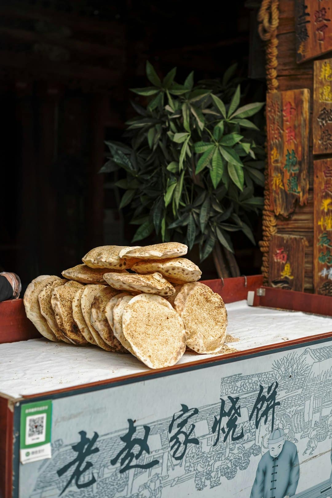 A stack of golden sesame flatbreads on a market stall.