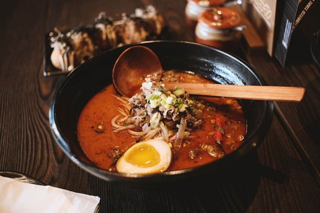 Steaming bowl of spicy ramen topped with beef and egg.