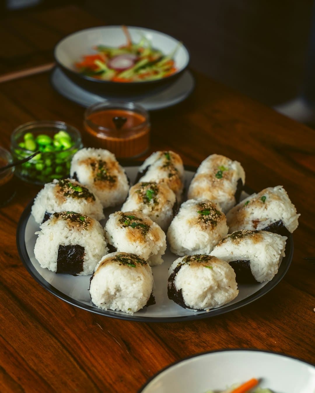 A platter of seasoned triangular rice balls on a wooden table.